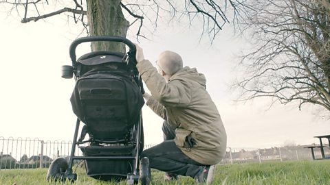 Back of pram and dad crouched down. 