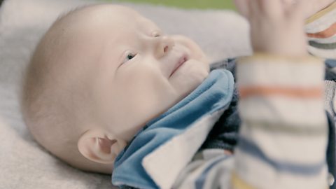 Baby lying down and smiling.