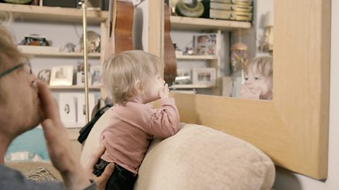 Dad and baby blowing kisses to a mirror. 