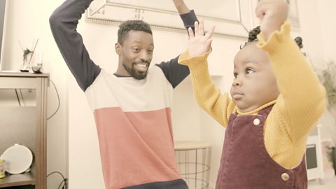 Dad and daughter with their arms up.