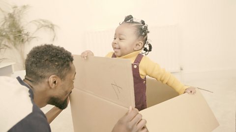 Dad and daughter playing peekaboo with a box.