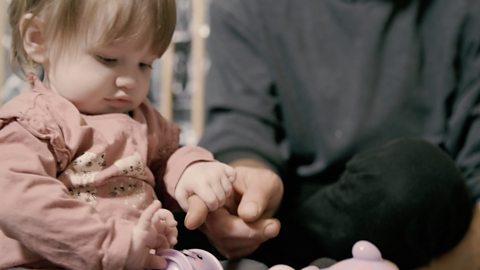 Baby holding dad's finger.