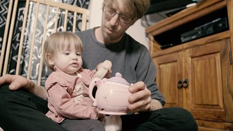 Dad and baby playing with teapots. 