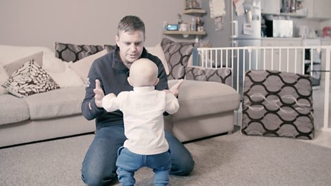 Dad and baby dancing in living room.