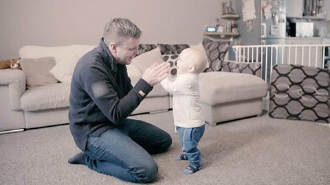 Dad and baby dancing together in living room.