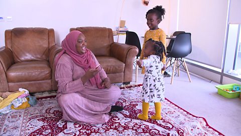 Mum sat on floor on a rug talking to her two little girls