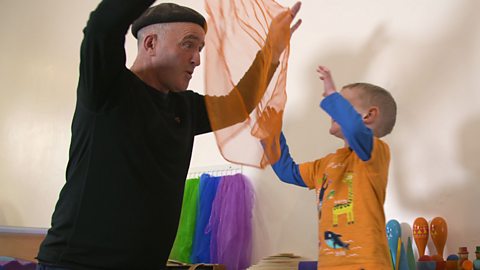 Dad holding up some orange netting to his little boy who is wearing orange clothes