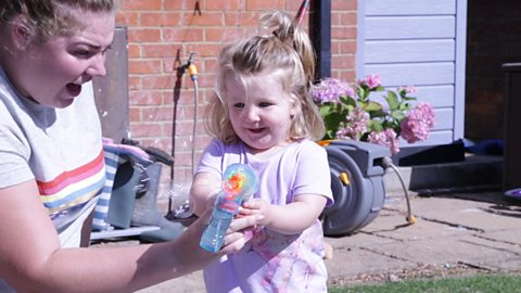 Girl holding water gun in the garden.