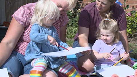 Mum dad and 2 daughters sat in garden colouring.