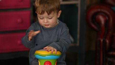 Boy hitting plastic drum.