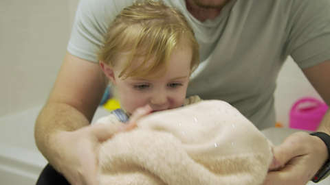 Close up of little girl drying her hands on a towel.