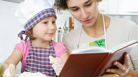 A mother and daughter look at a cookery book