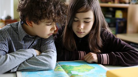 Two children look at an atlas