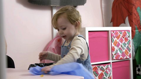 Little girl wiping a table with a blue cloth.