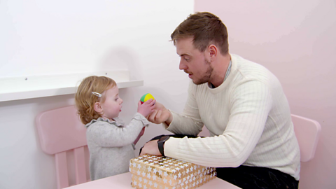 Dad and little girl holding multi-coloured ball.