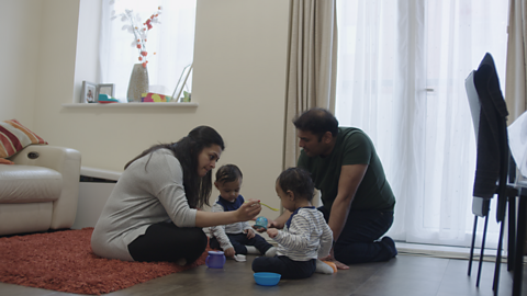 Mum and dad sat on floor talking to their two toddlers.