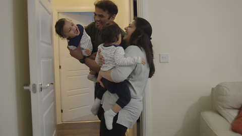 Two toddlers being held by mum and dad and laughing