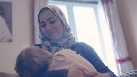 Mum cradling baby and looking at them.