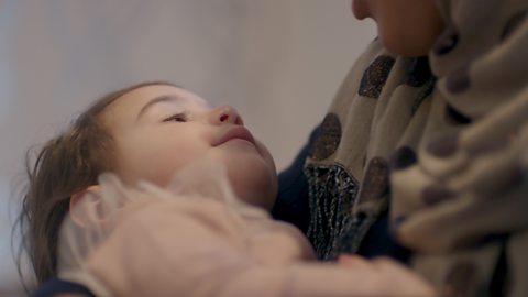 Baby staring up at mum holding them.