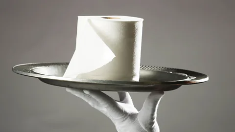 A roll of toilet paper on a silver platter.