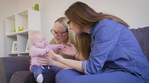 Two mums talking to their baby girl.