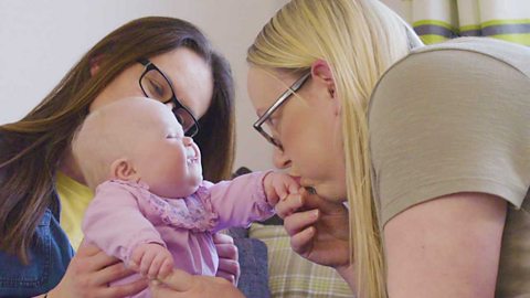 A mum blowing a raspberry on her baby's hand.