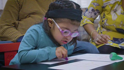 A little girl drawing with a crayon.