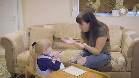 A mum saying 'ball' and making a round action with her hands.