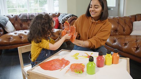 A mum and her daughter playing with finger paints.