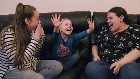 A little boy singing with his mum and older sister.