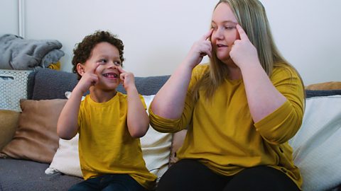 A little boy and his mum singing head, shoulders, knees and toes.