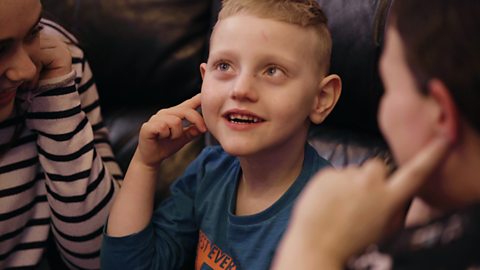 A little boy pointing to his ear.