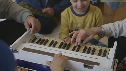 Family sitting around a harmonium.