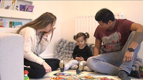 Family sat on floor with toys.