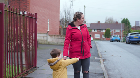 Boy pointing across a road with mum