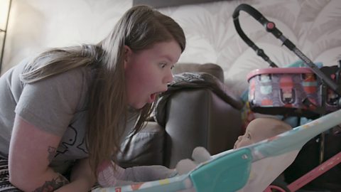 Mum pulling silly face at baby who is sat in a bouncer seat