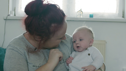 Mum holding and looking at baby.