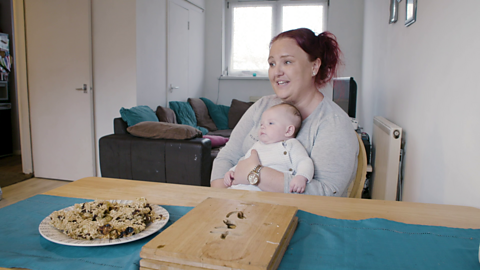 Mum sat at table holding baby.