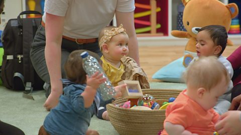 A grips of babies sat dow paling with items in a basket.