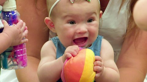 A baby holding a ball.