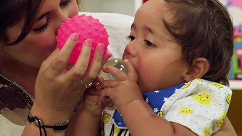 Mum and baby holding two balls.