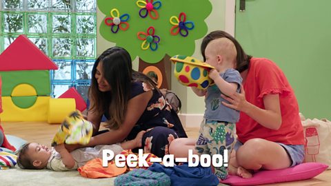 Two babies with their mum's playing with hats.