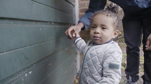 Toddler touching a garage door. 