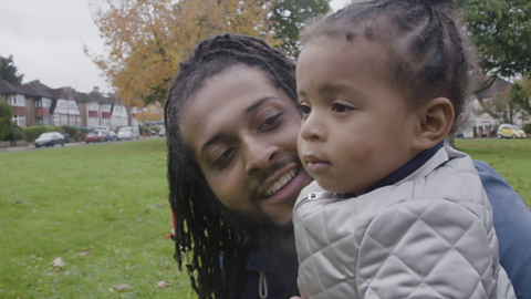 Dad bending down to talk to child.