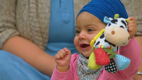 A small baby baby holding a toy squishy cow.