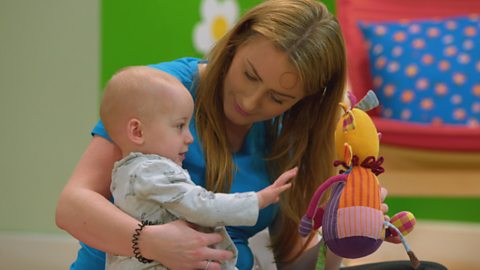 A mother with her child, the mother is holding a soft toy.