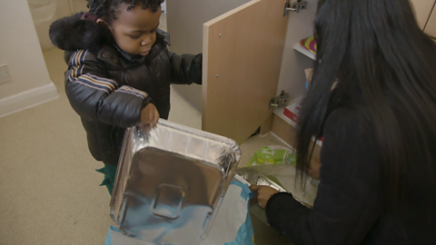 Toddler holding a foil tray.