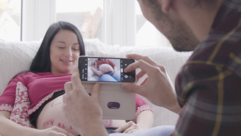 Dad taking picture of his pregnant partner