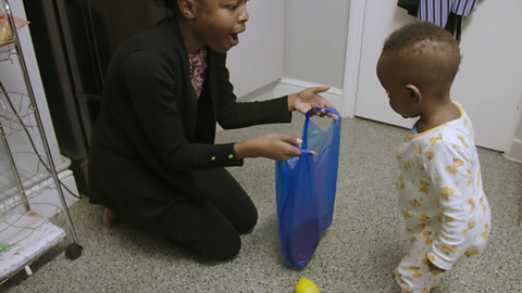 Mum holding bag open for her toddler.