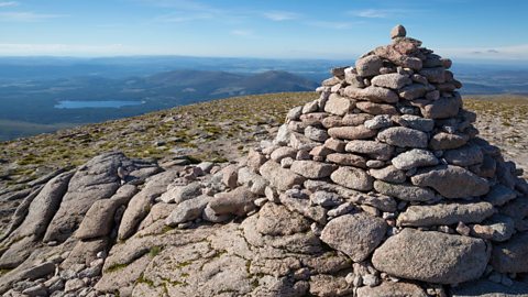 A stone cairn on the summit of Cairn Gorm mountain, looking to the valley below